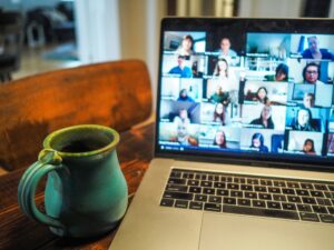 cup of coffee next to a computer with Zoom attendees